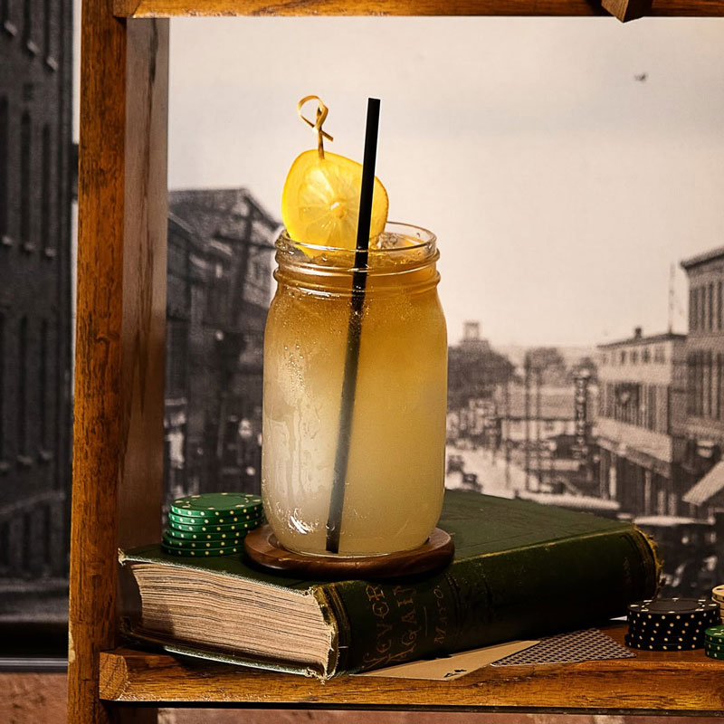 The Gentleman’s Sour Cocktail sitting on a book with poker chips